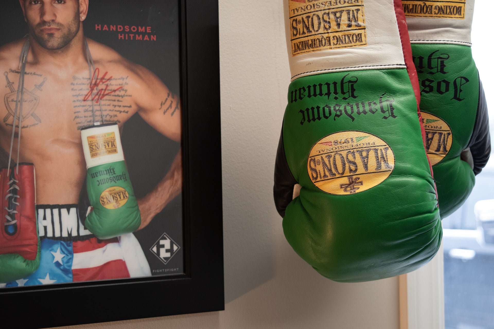 Green boxing gloves with 'Masonic' branding next to a framed picture of a shirtless man holding green boxing gloves.