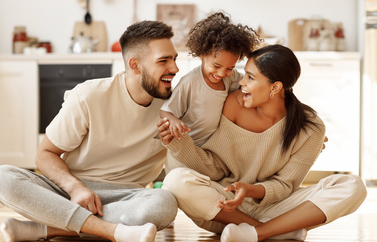 Family of three sitting together on the floor in a kitchen