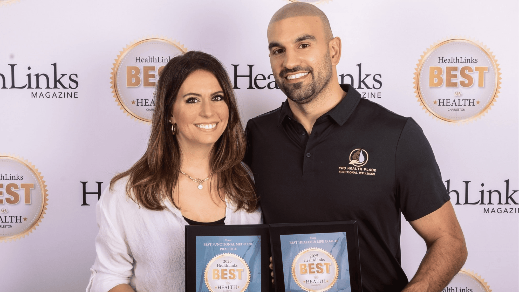 Two people posing with an award in front of a backdrop with 'HealthLinks Magazine' logos.