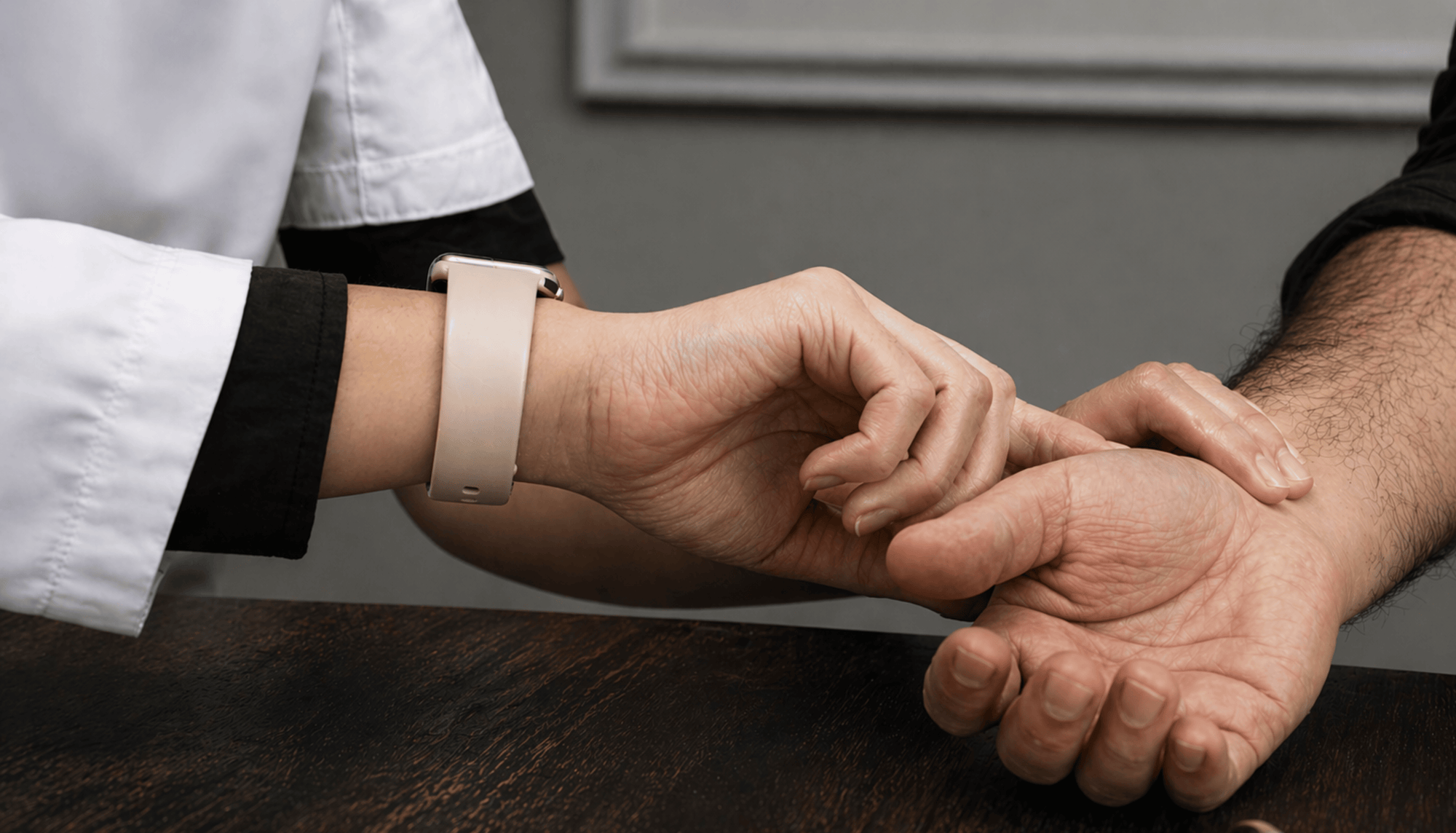 Close-up of a person's hand being held by another person, with a neutral background.