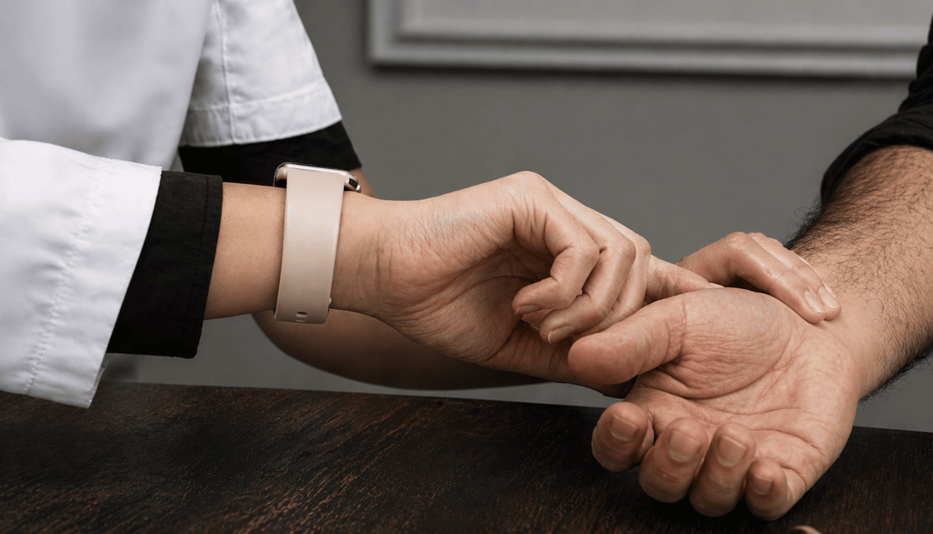 Close-up of a person's hand being held by another person, with a neutral background.